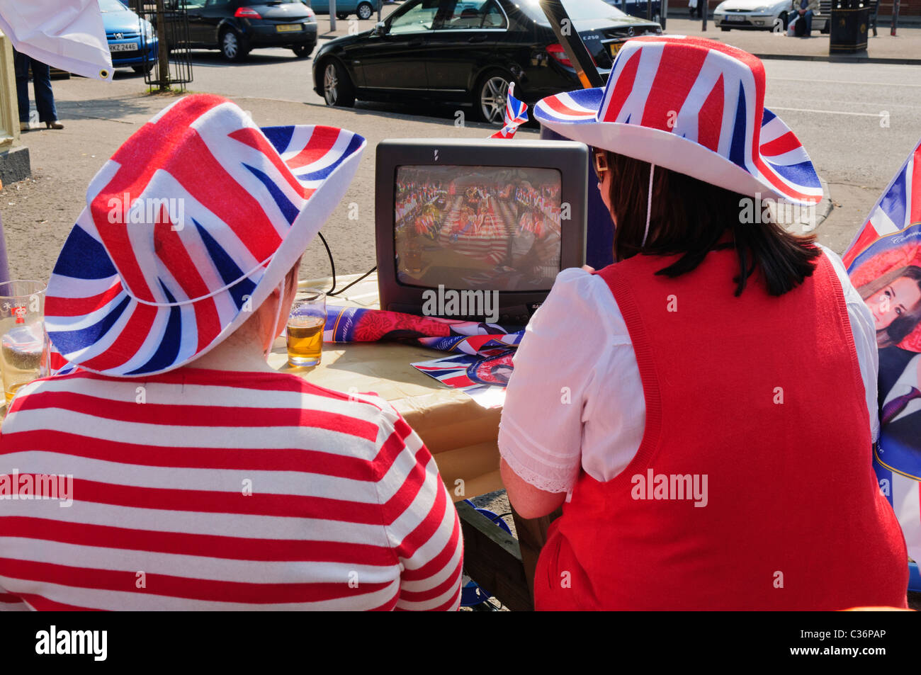 Due donne al di fuori seduta, guarda il Royal Wedding su un piccolo televisore portatile Foto Stock