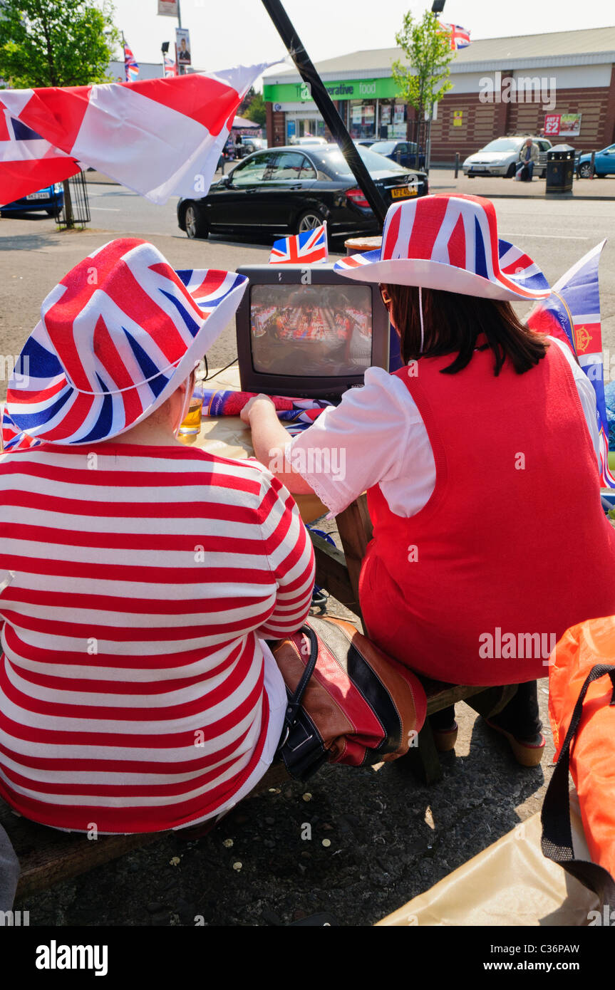 Due donne al di fuori seduta, guarda il Royal Wedding su un piccolo televisore portatile Foto Stock