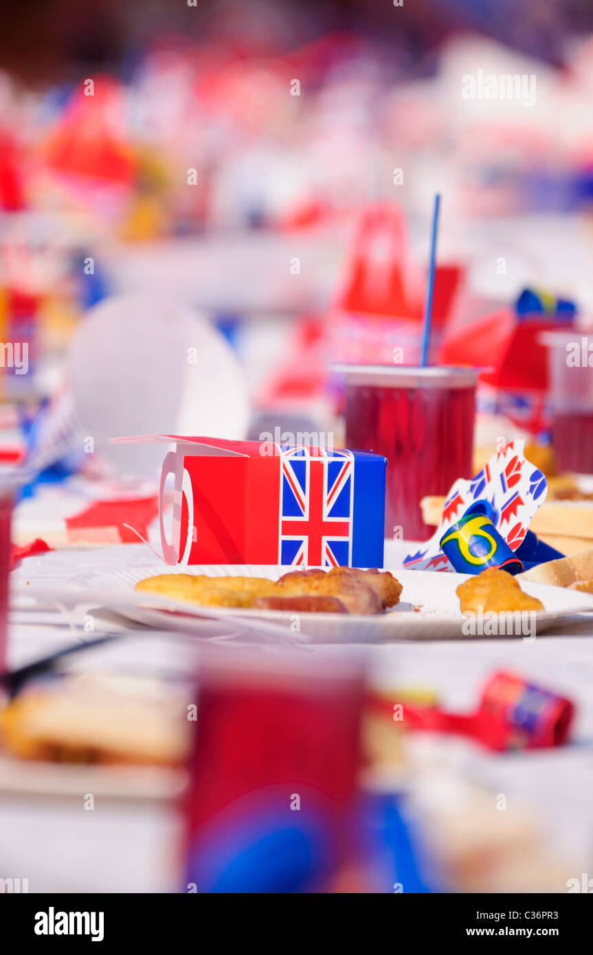 I bambini si siedono a lunghi tavoli con rosso, bianco e blu gli accessori di altri produttori a un evento reale partito di strada Foto Stock