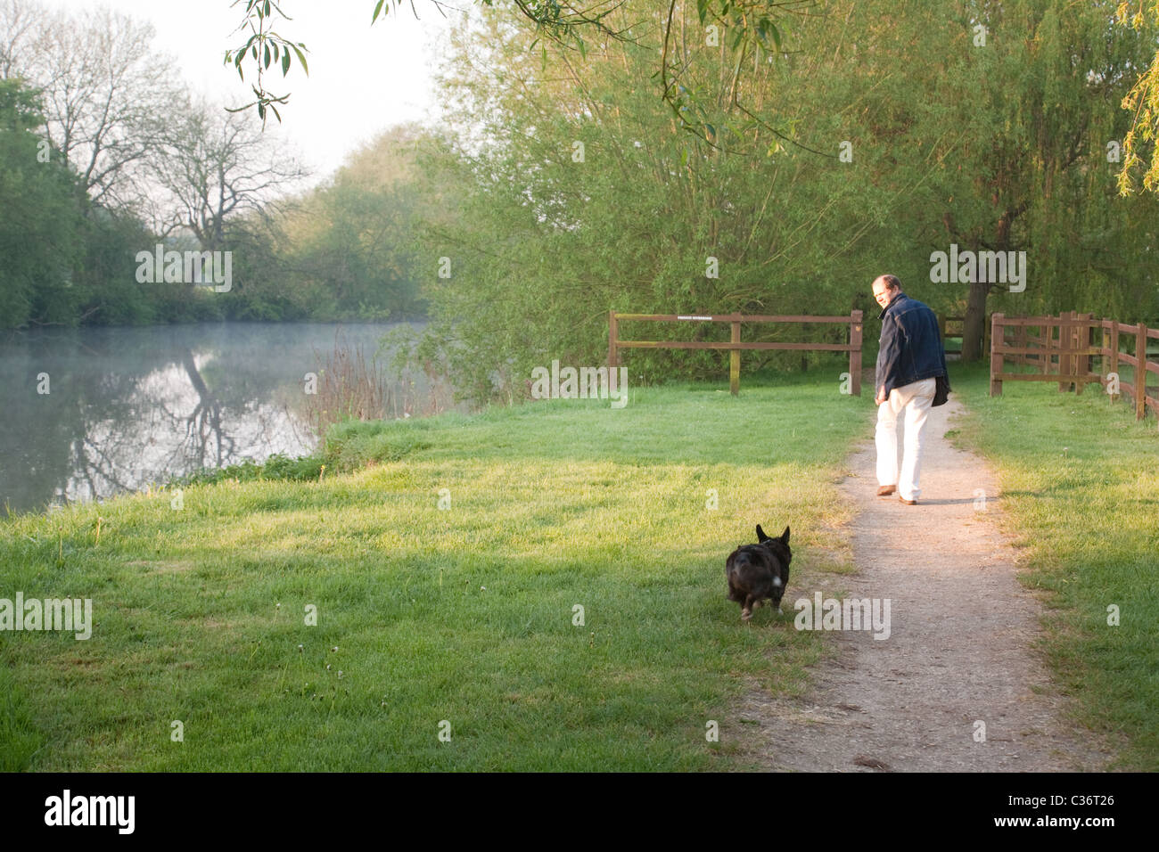 Un uomo che cammina il suo cane lungo il Tamigi percorso in primavera, a Wallingford, Oxfordshire, Regno Unito Foto Stock