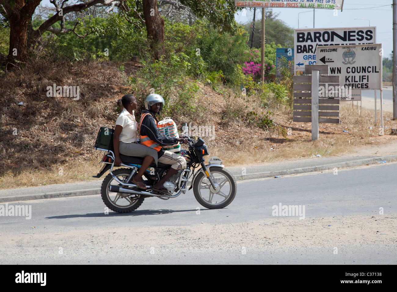 Donna africana passeggero sul retro del motociclo taxi o piki piki Mombasa Kenya Foto Stock