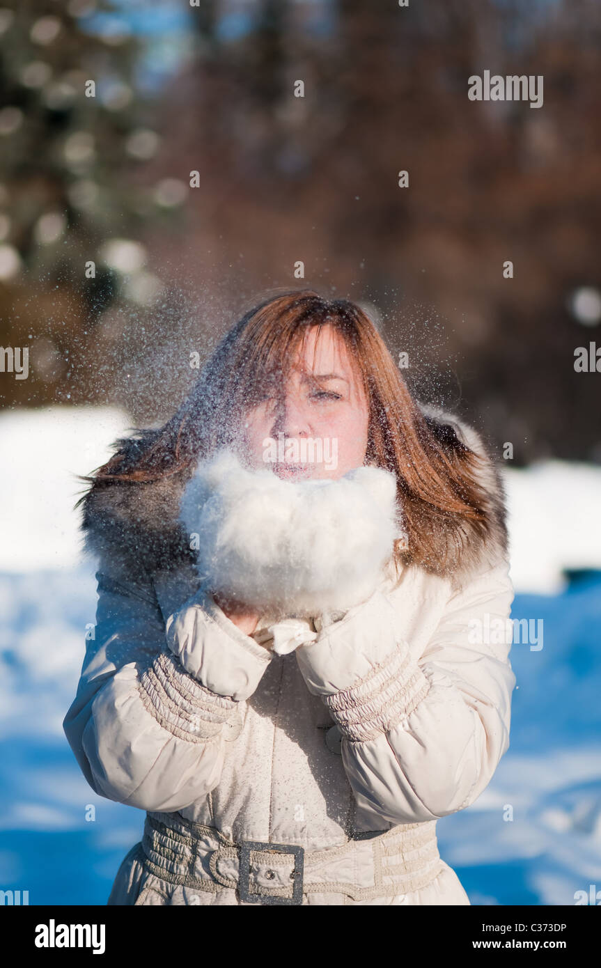 Bella donna che soffia nella neve Foto Stock