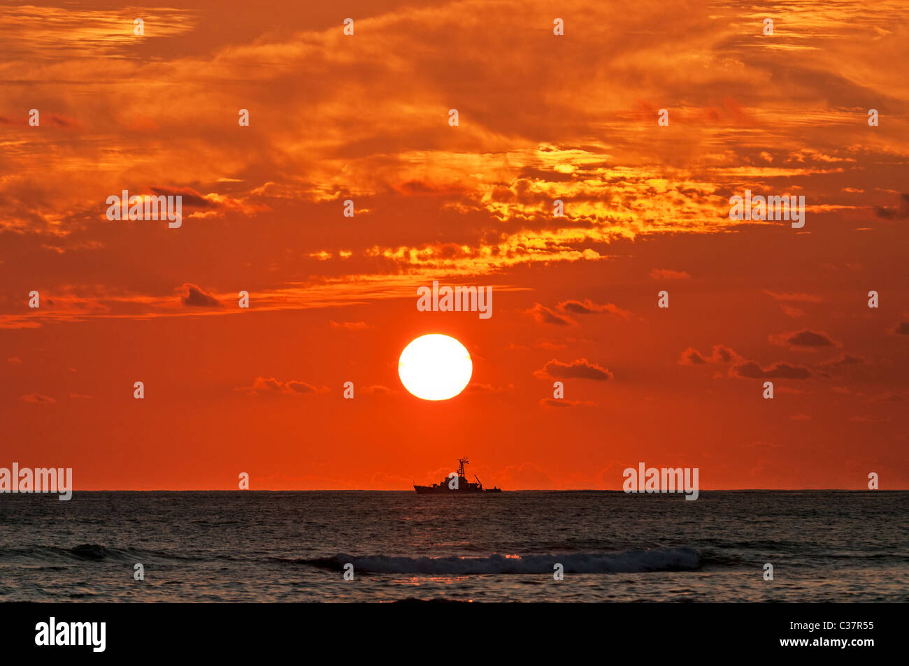 Un United States Coast Guard taglierina si stagliano dal sole al tramonto, come si vede da Waikiki, Honolulu, Hawaii. Foto Stock