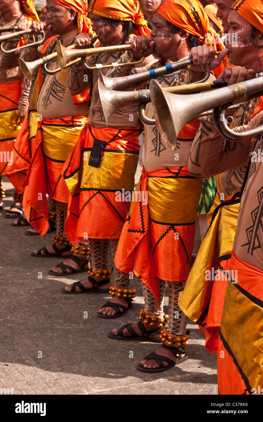 Buglers vestito in vivaci costumi tribali soffiare i loro strumenti durante il Festival Aliwan a Manila Foto Stock