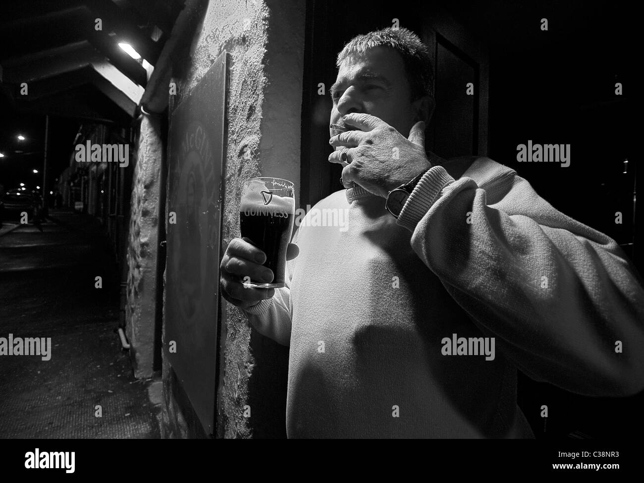 Un uomo gode di una pinta di Guinness al di fuori Sissy McGinty's Pub, Castlerea, nella contea di Roscommon, Irlanda. Foto Stock