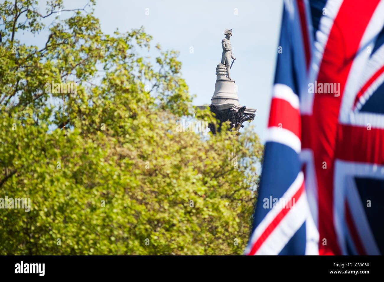 Statua di Horatio Lord Nelson sulla parte superiore della colonna di Nelson in Trafalgar Square visto da un centro commerciale con una bandiera europea Foto Stock