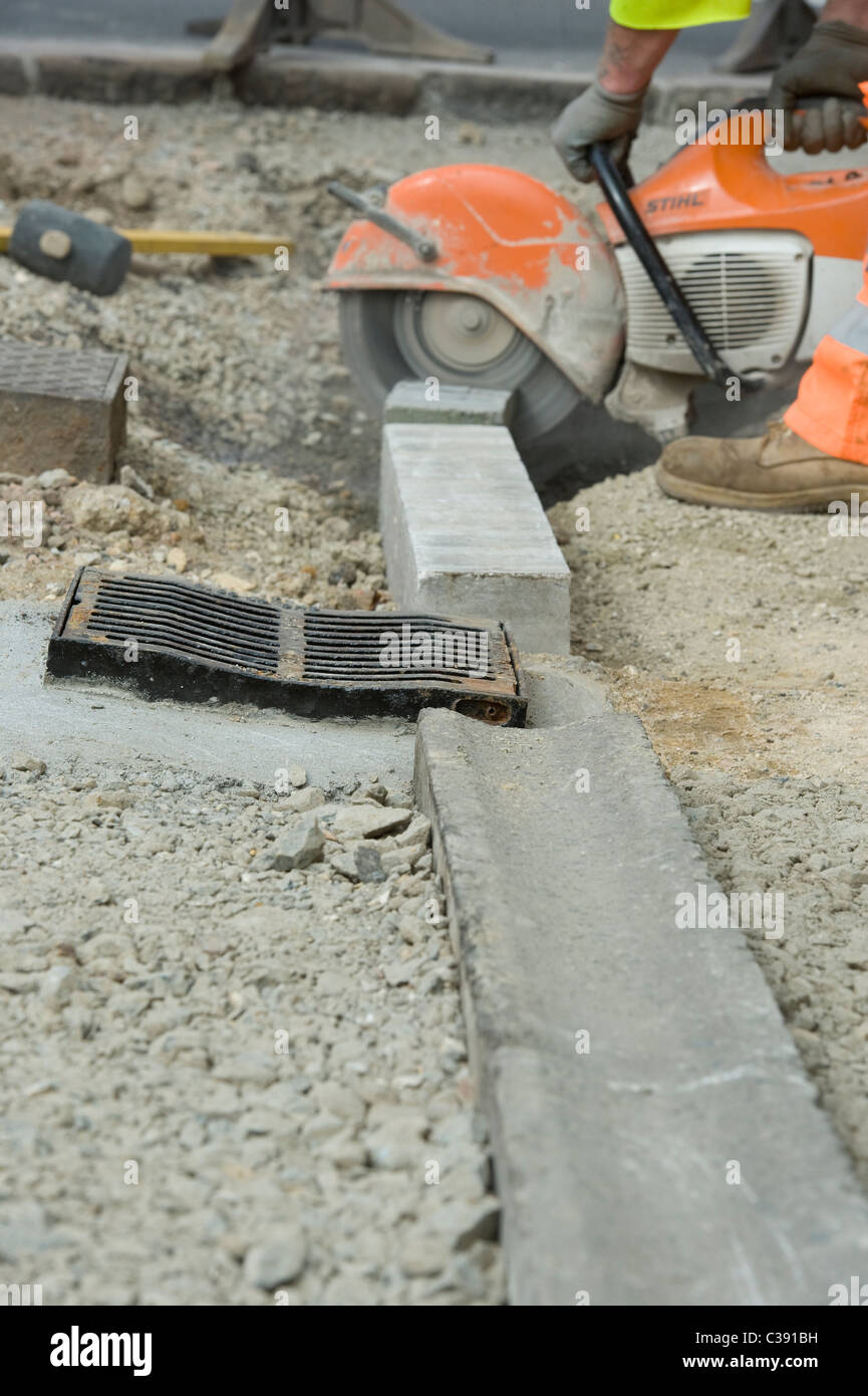 Roadworks: lavoratori utilizzano pietra apparecchiature di taglio di pavimentazione laici in East Sussex. Foto Stock