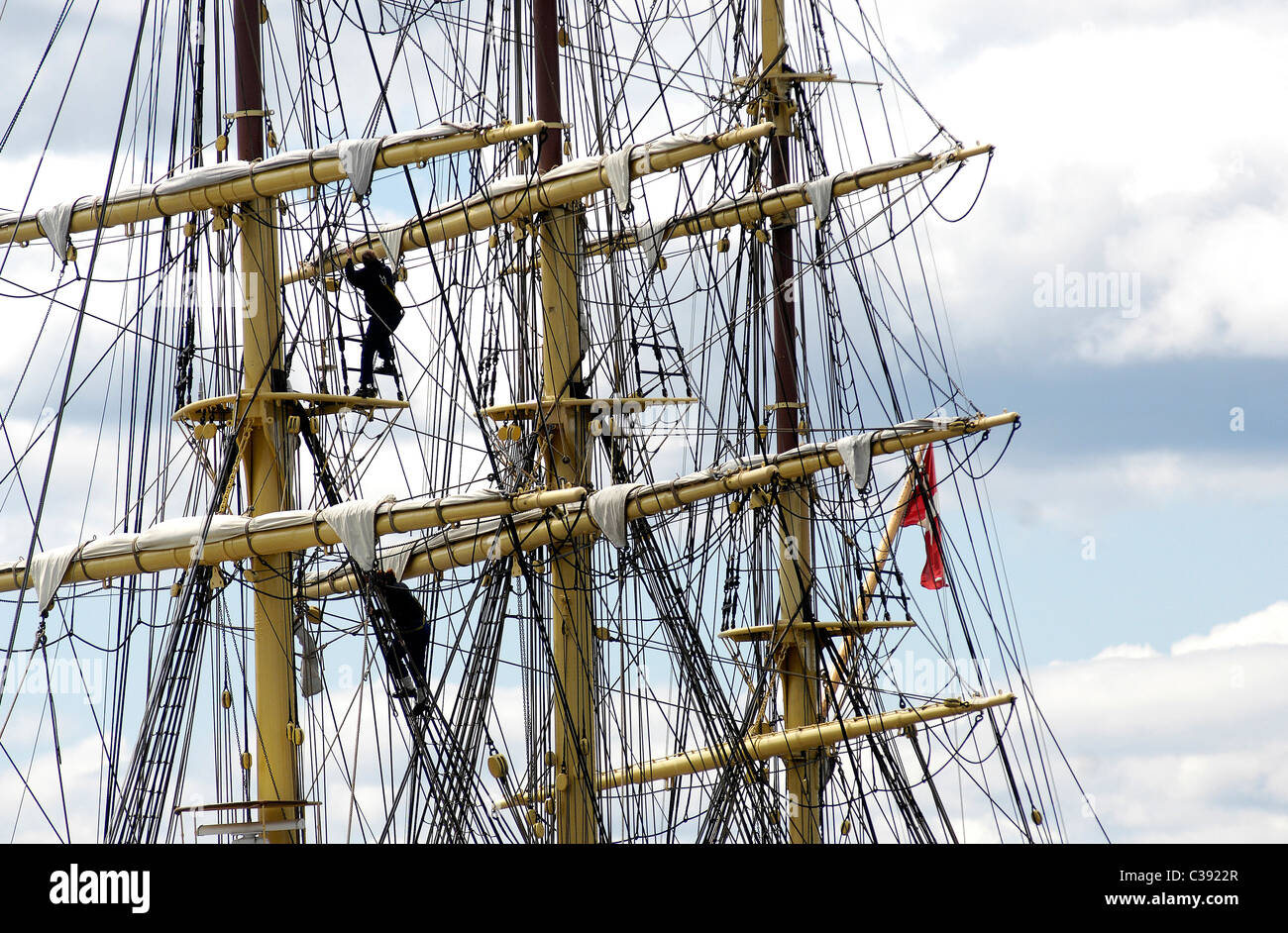 Un membro di equipaggio si arrampica per le manovre su il danese tall ship Georg Stage come si naviga fino al fiume Clyde in Scozia. Foto Stock Un membro di equipaggio si arrampica per le manovre su il danese tall ship Georg Stage come si naviga fino al fiume Clyde in Scozia. Foto Stock