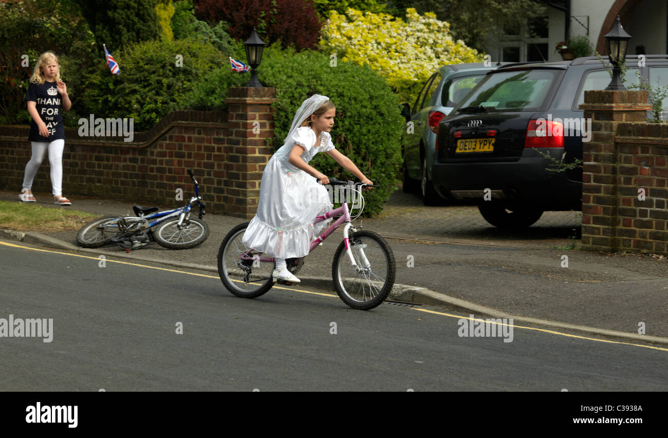 Giovane ragazza vestita come una sposa la fuga in sella a una moto dal Royal Wedding Street Party Foto Stock