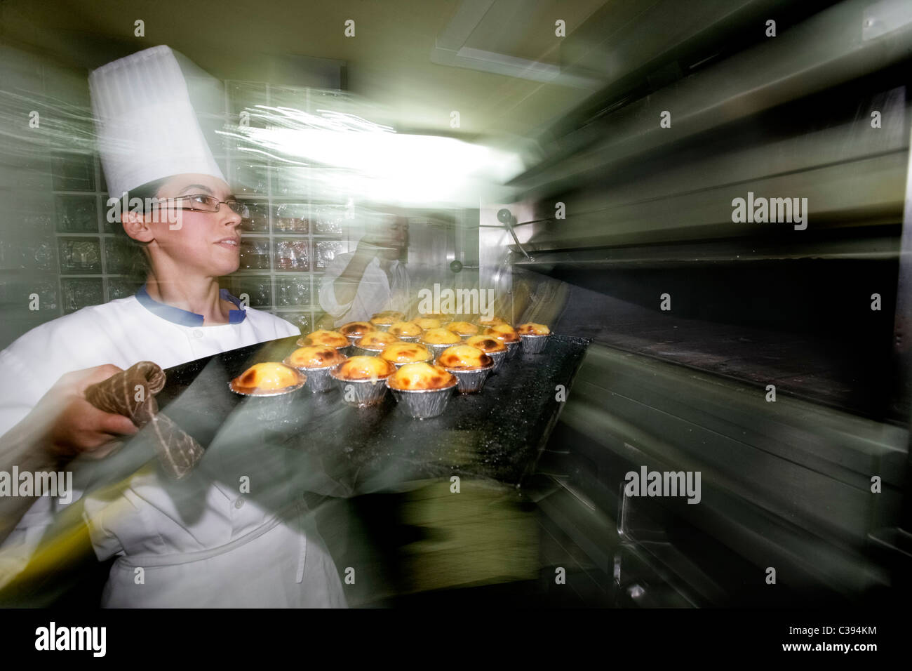 Donna pasticcere tenendo tipico dolce portoghese Pasteis de nata fuori del forno di un ristorante cucina Foto Stock