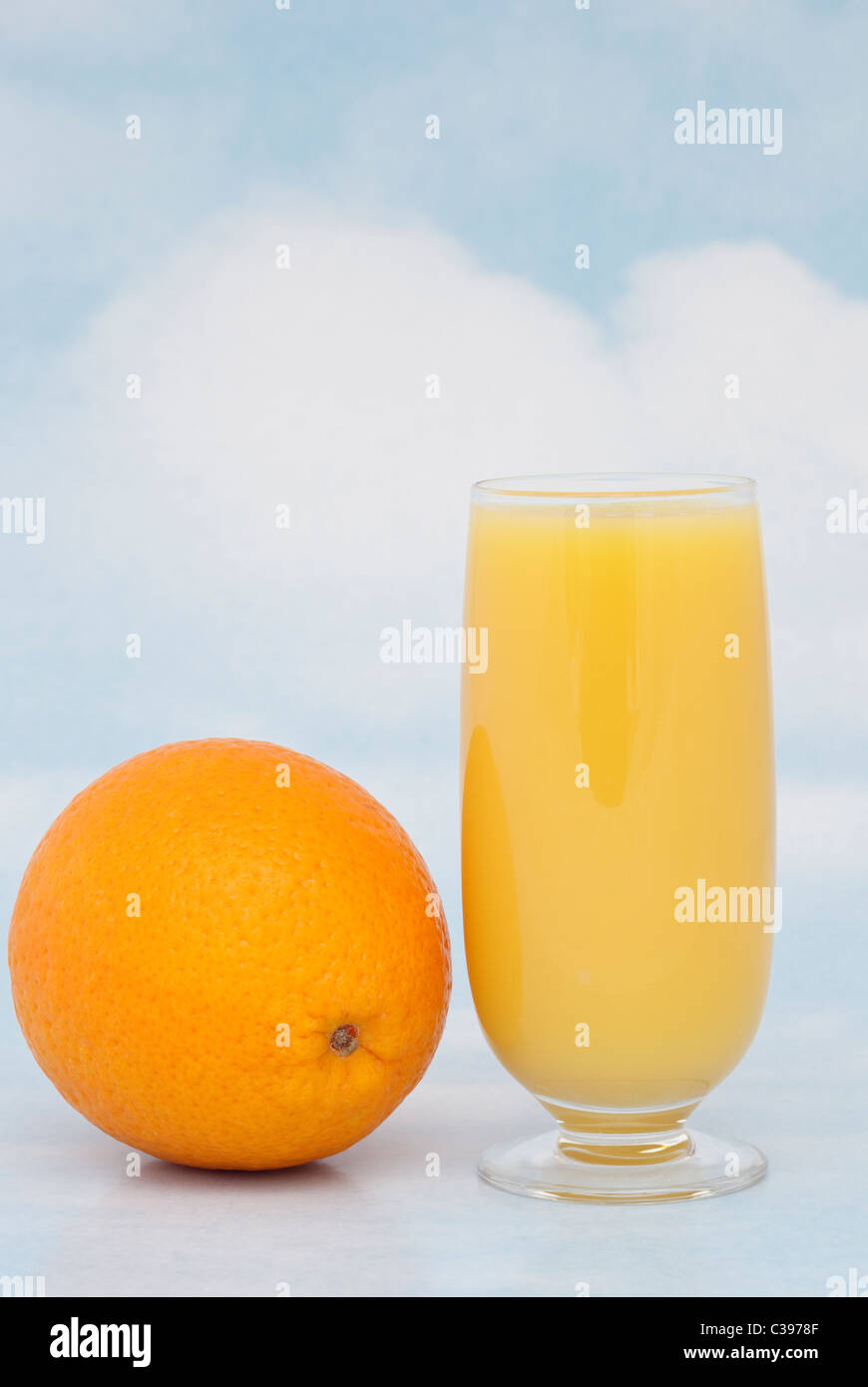 Un bicchiere di succo d'arancia fresco con un tutta arancione contenenti vitamina C contro un cielo blu sullo sfondo. Inghilterra Regno Unito Gran Bretagna Foto Stock