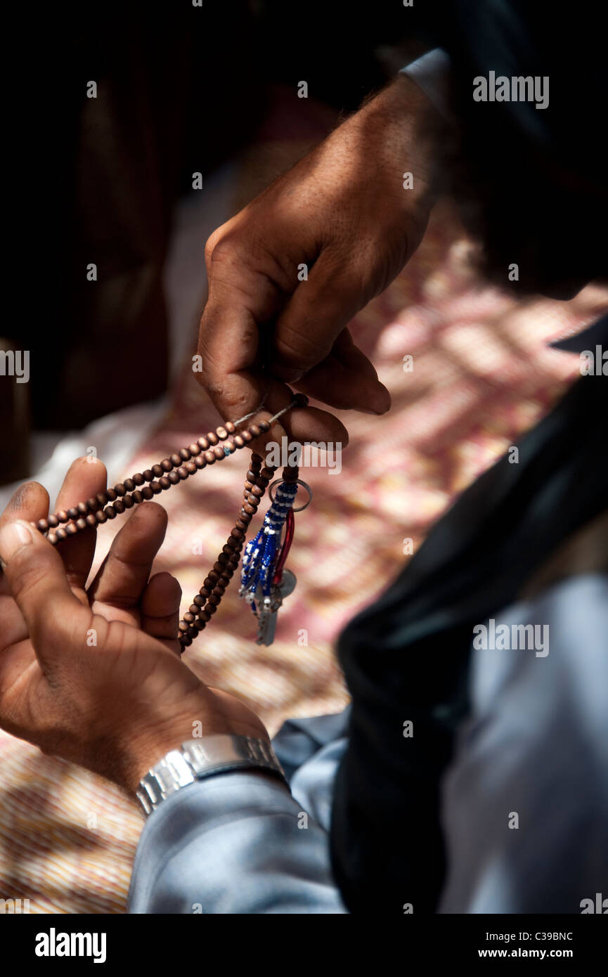 Uomo con la preghiera di perline in Helmand in Afghanistan Foto Stock