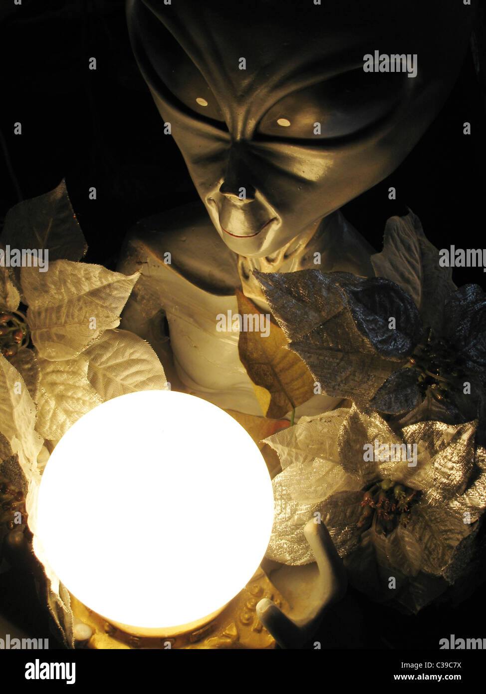 Statuetta di alien con sfera nelle tenebre Foto Stock