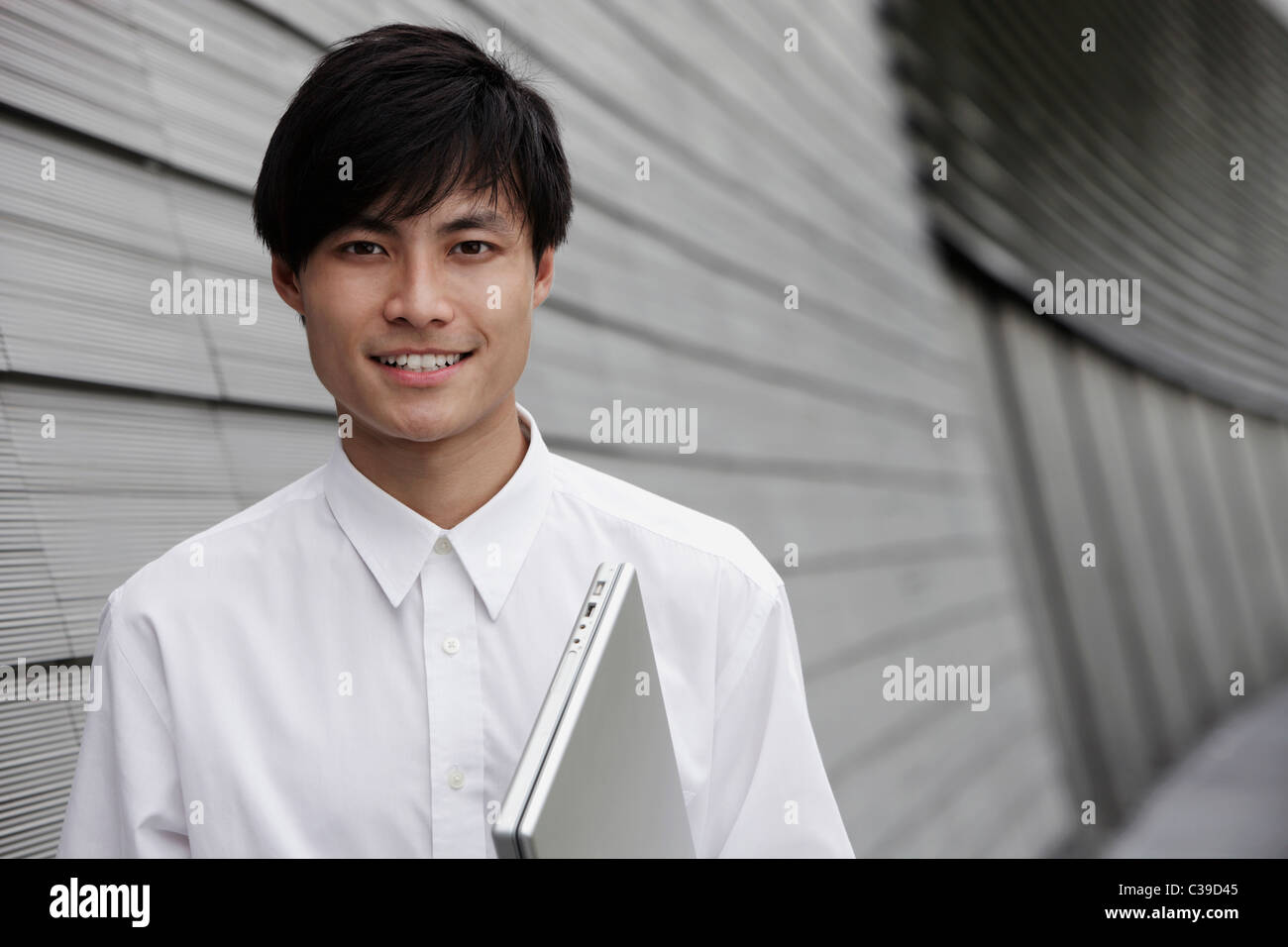 L'uomo tenendo premuto lap top accanto a un edificio Foto Stock