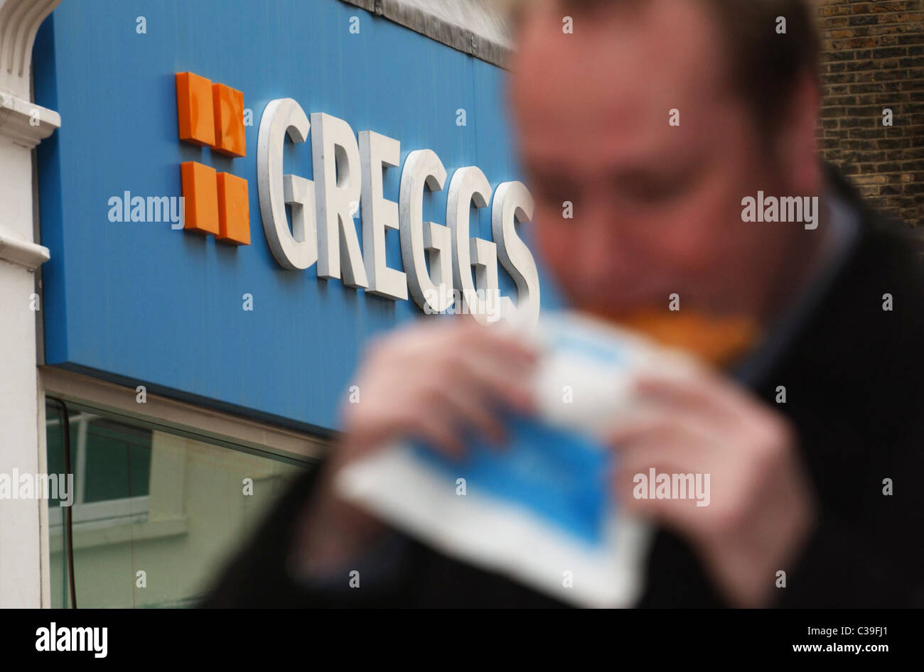 L'immagine mostra: un lavoratore della città di mangiare a Greggs pasty. Foto Stock