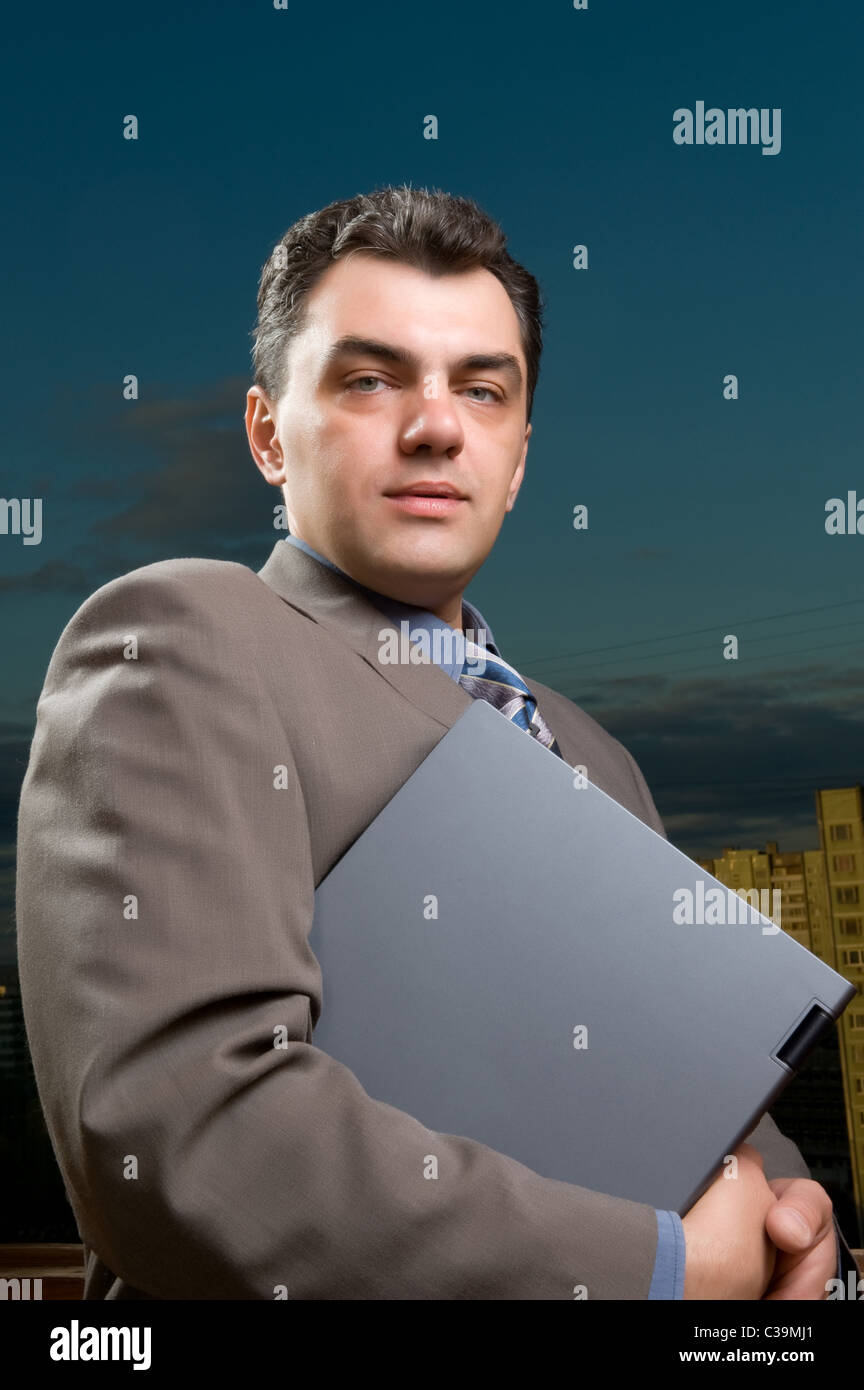 Uomo in una tuta contro il cielo di sera con il computer portatile Foto Stock