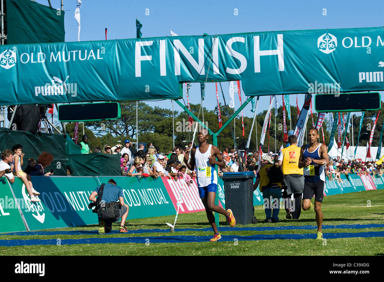 I corridori attraversano la finitura del 5km Fun Run, Two Oceans Marathon, Cape Town, Sud Africa Foto Stock
