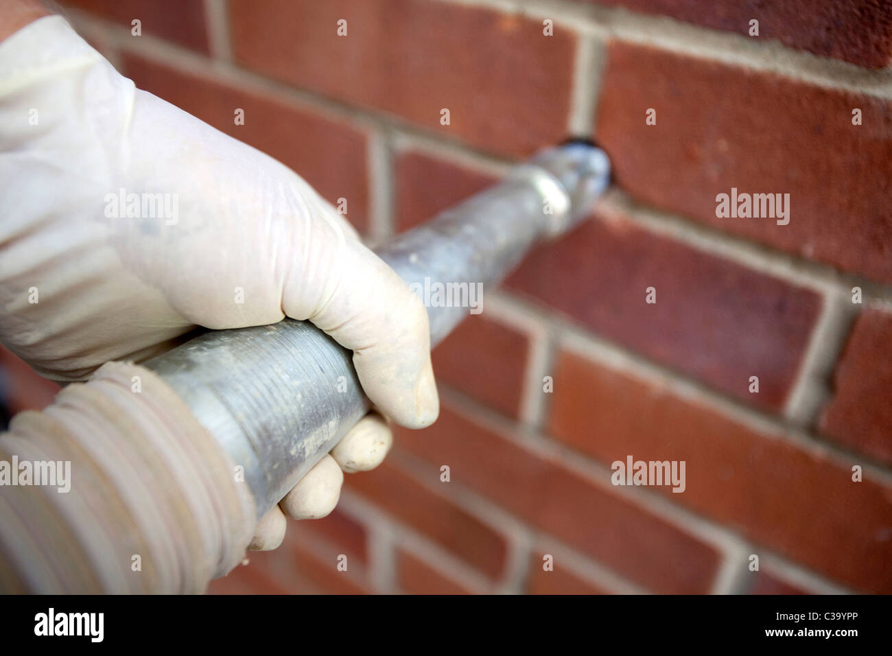 Immagine illustrativa della parete di cavità di isolamento. Un lavoratore di totale isolamento tubi soluzioni Rockwool in una cavità della parete. Foto Stock