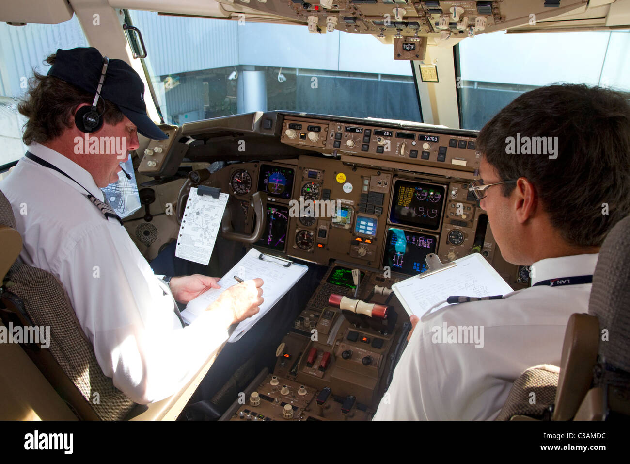 Il pilota e il primo ufficiale la revisione di una pre-volo lista di controllo nella cabina di pilotaggio di un Boeing 767. Foto Stock