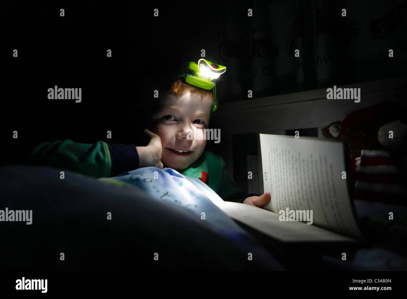 https://c8.alamy.com/compit/c3ar0n/a-sette-anni-di-vecchio-ragazzo-per-leggere-un-libro-nel-suo-letto-utilizzando-una-lampada-da-testa-c3ar0n.jpg