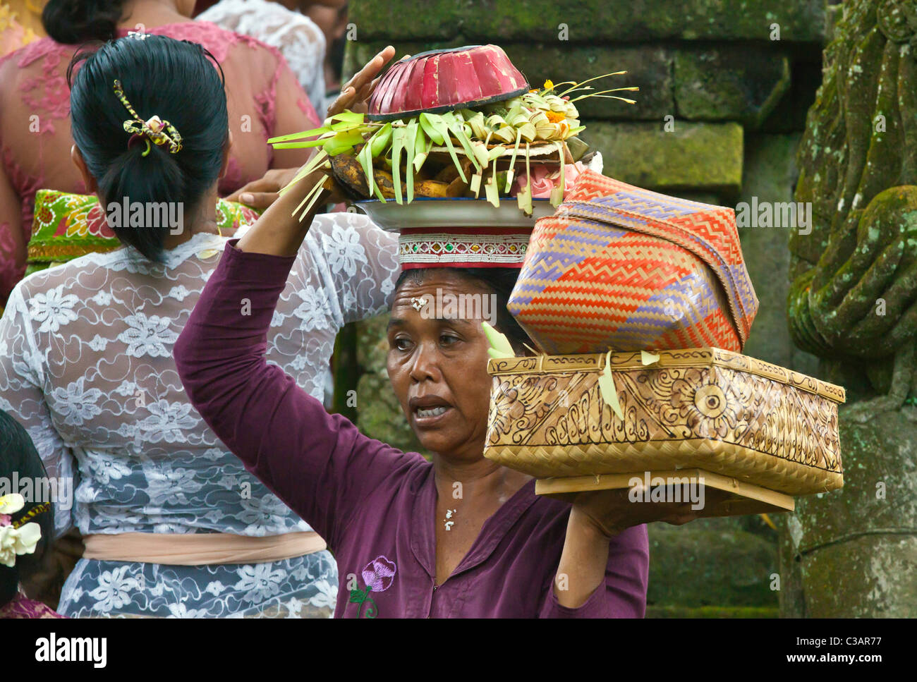 Donna indù offerte di riporto bilanciata sui capi alla cerimonia di anniversario di pura PRAJAPATI nei pressi di Ubud - BENTUYUNG SAKTI, BALI Foto Stock