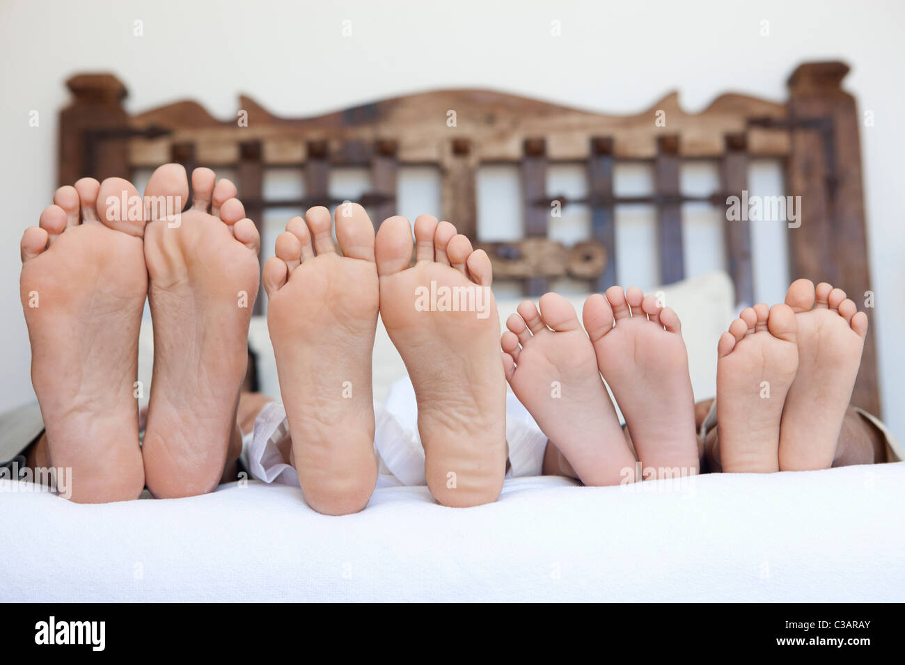 Famiglia giacente sul letto, piedi allineati Foto Stock