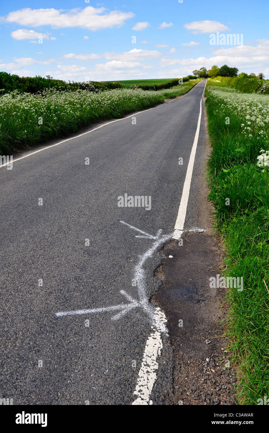Pot foro contrassegnato per la riparazione su una tranquilla strada di campagna nel Bedfordshire Foto Stock