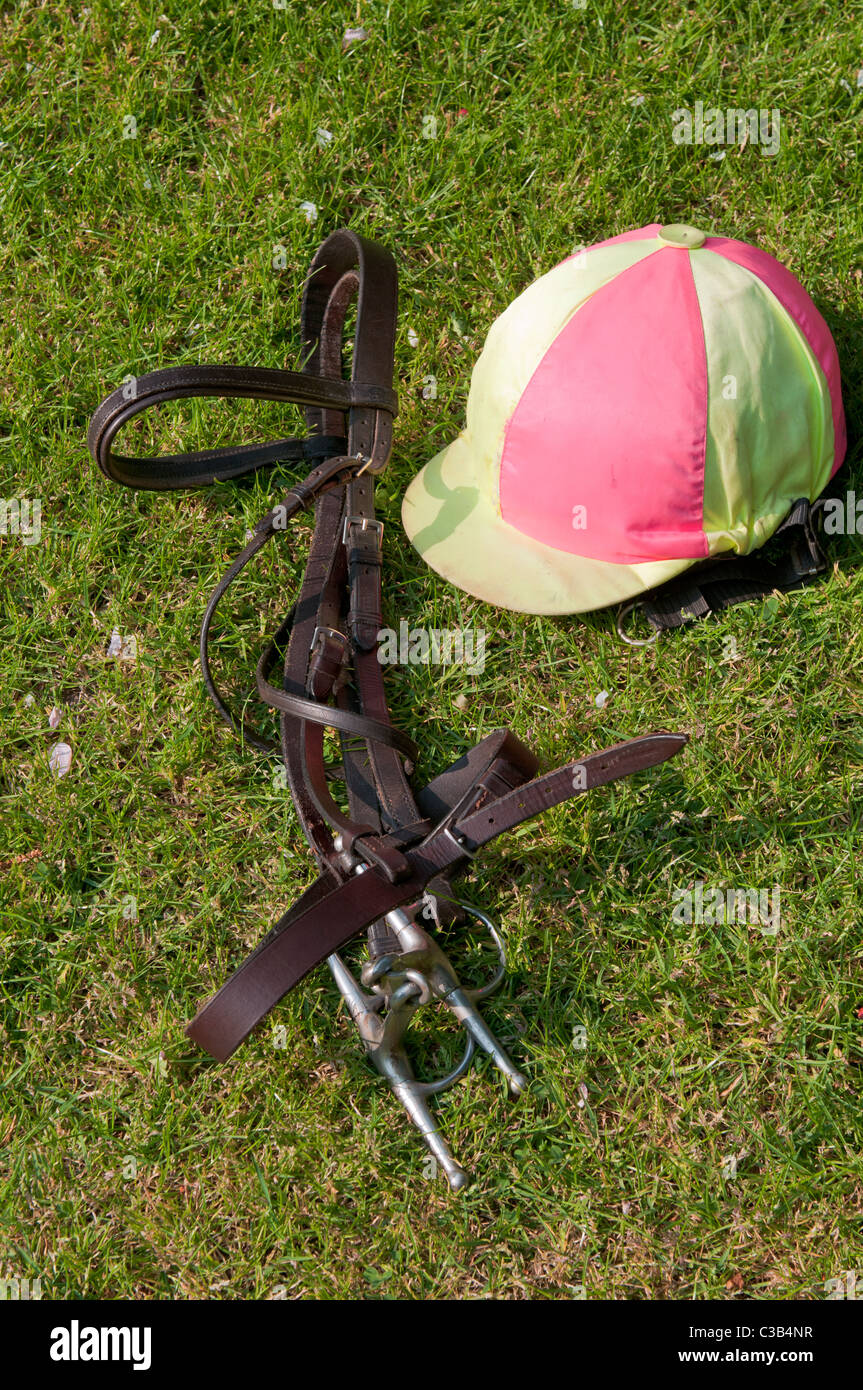 Briglia in cuoio e Jockey calotta cranica su equestre di erba Foto Stock