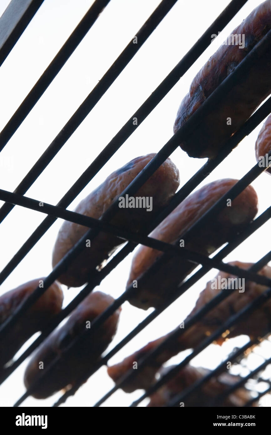 Vista da sotto di una griglia per il barbecue con salsicce e cottura del pollo Foto Stock