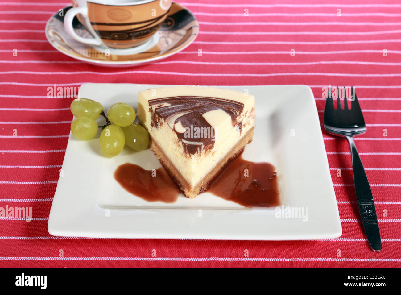 Farfalla di turbolenza del cioccolato torta di formaggio su una piastra con uve e salsa di caffè Foto Stock