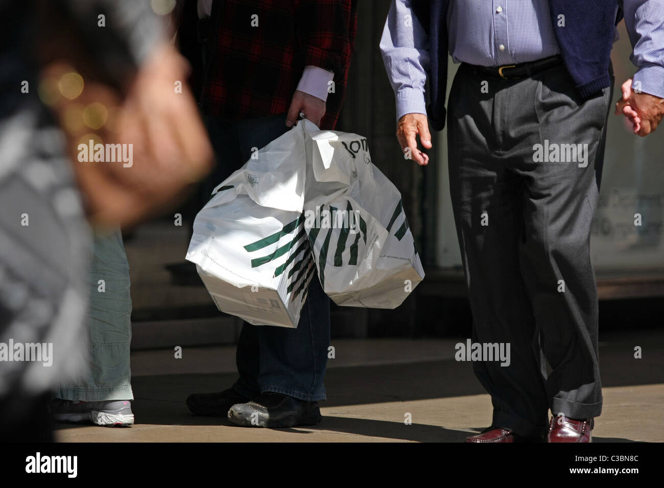 Parte di una persona che porta John Lewis borse per lo shopping in Oxford Street a Londra, Inghilterra Foto Stock