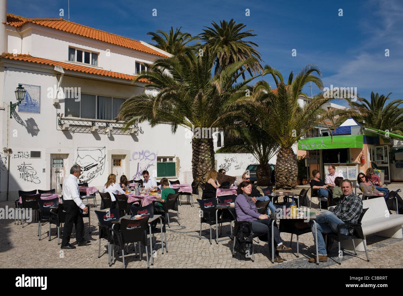 I turisti mangiare all'aperto nel piacevole clima balneare di Cascais, Portogallo Foto Stock