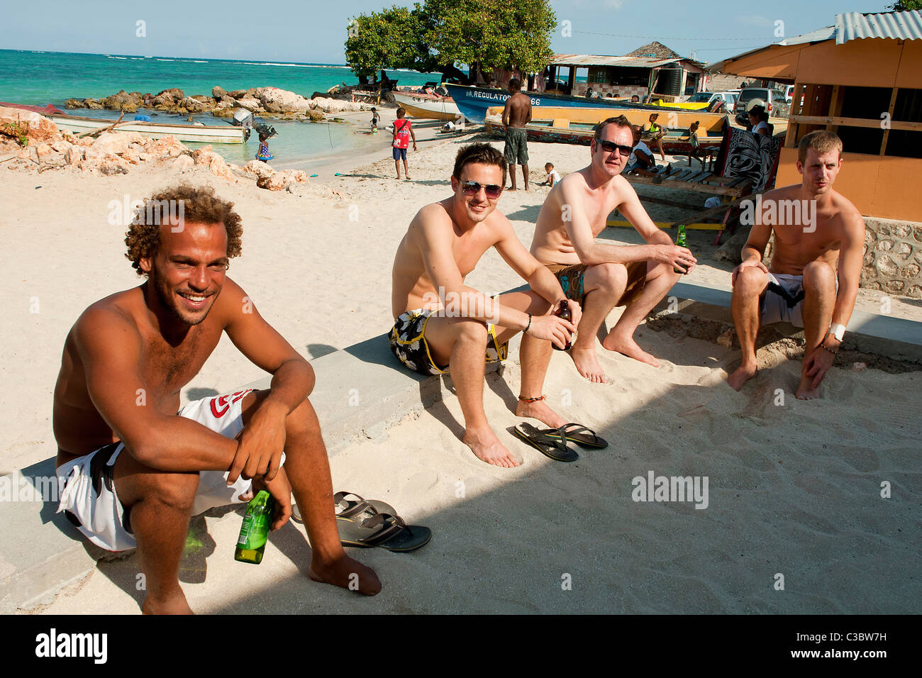 Quattro amici sul bere birra a Hellshire beach vicino a Kingston, Giamaica. Foto Stock