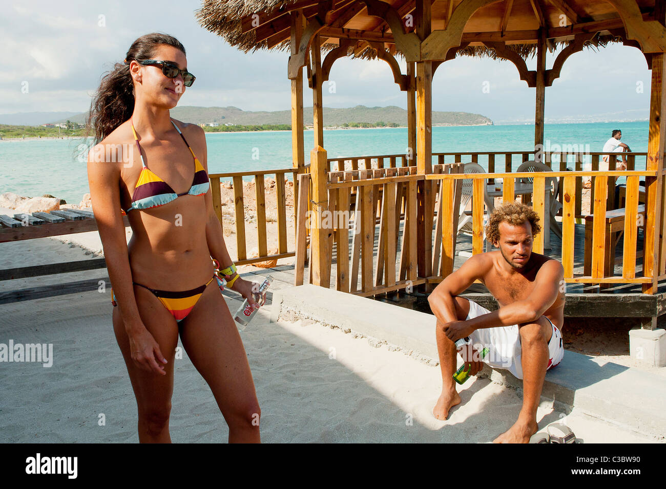 Una giovane donna in un bikini con un amico maschio a Hellshire beach vicino a Kingston, Giamaica. Foto Stock