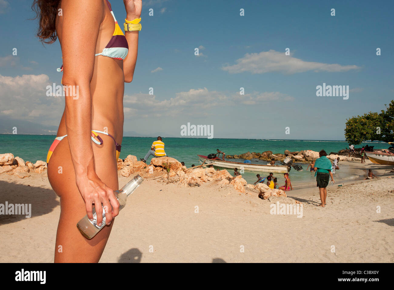 Una donna in bikini con una bottiglia di Smirnoff Ice a Hellshire beach in Giamaica. Foto Stock