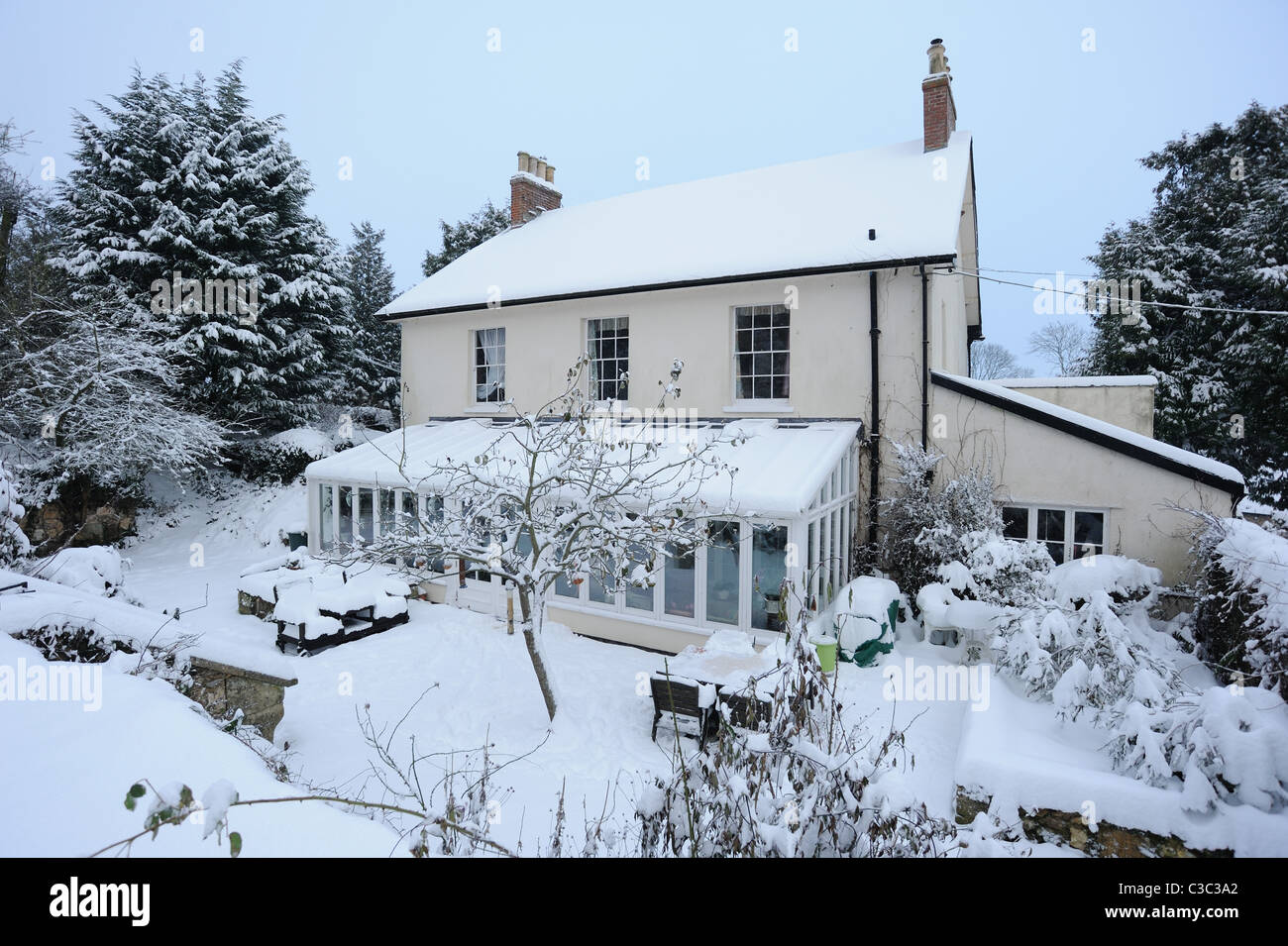 Country house, conservatorio e coperta di neve giardino in un freddo giorno mattina in East Devon Foto Stock