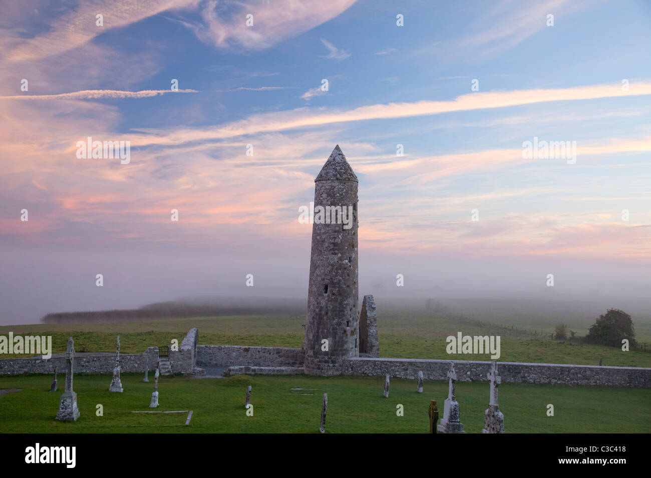 Dawn mist intorno al tempio e Finghin round tower, Monastero di Clonmacnoise, nella contea di Offaly, Irlanda. Foto Stock