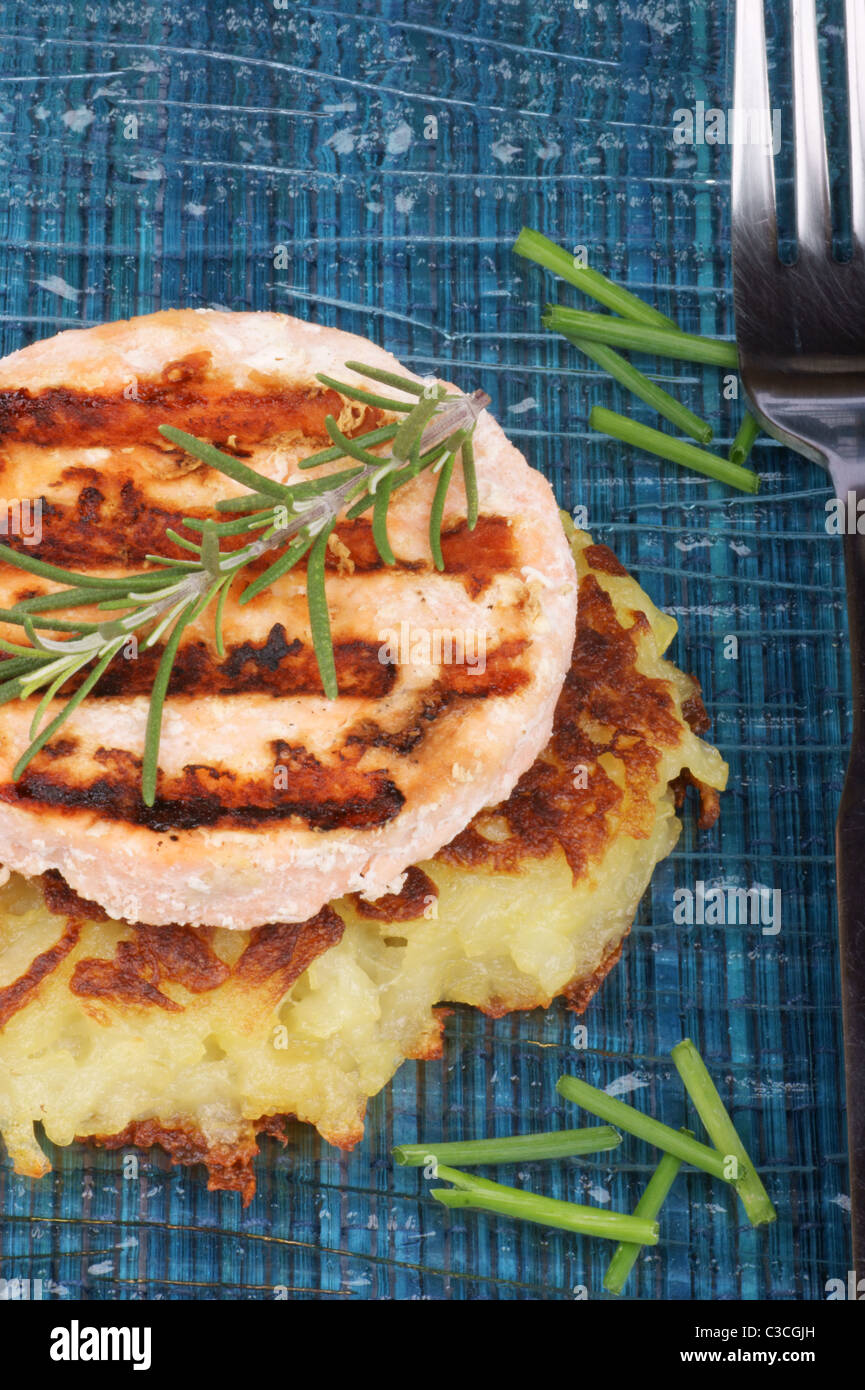 Roesti e salmone alla griglia con erba cipollina e rosmarino su un piatto di vetro Foto Stock