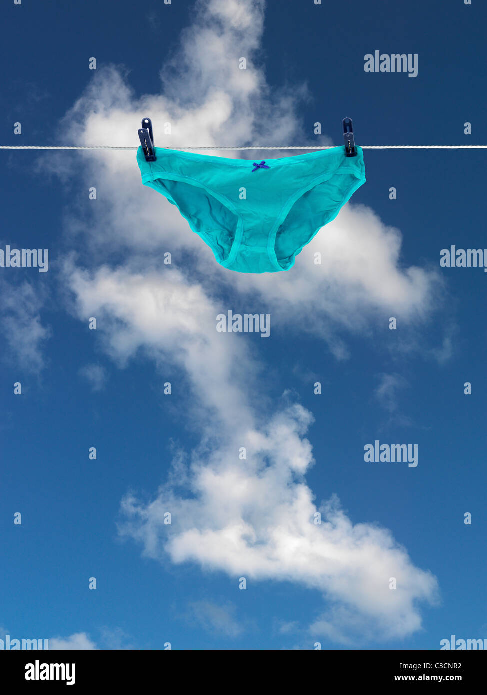 I vestiti su una linea di abbigliamento isolata contro un cielo blu Foto Stock