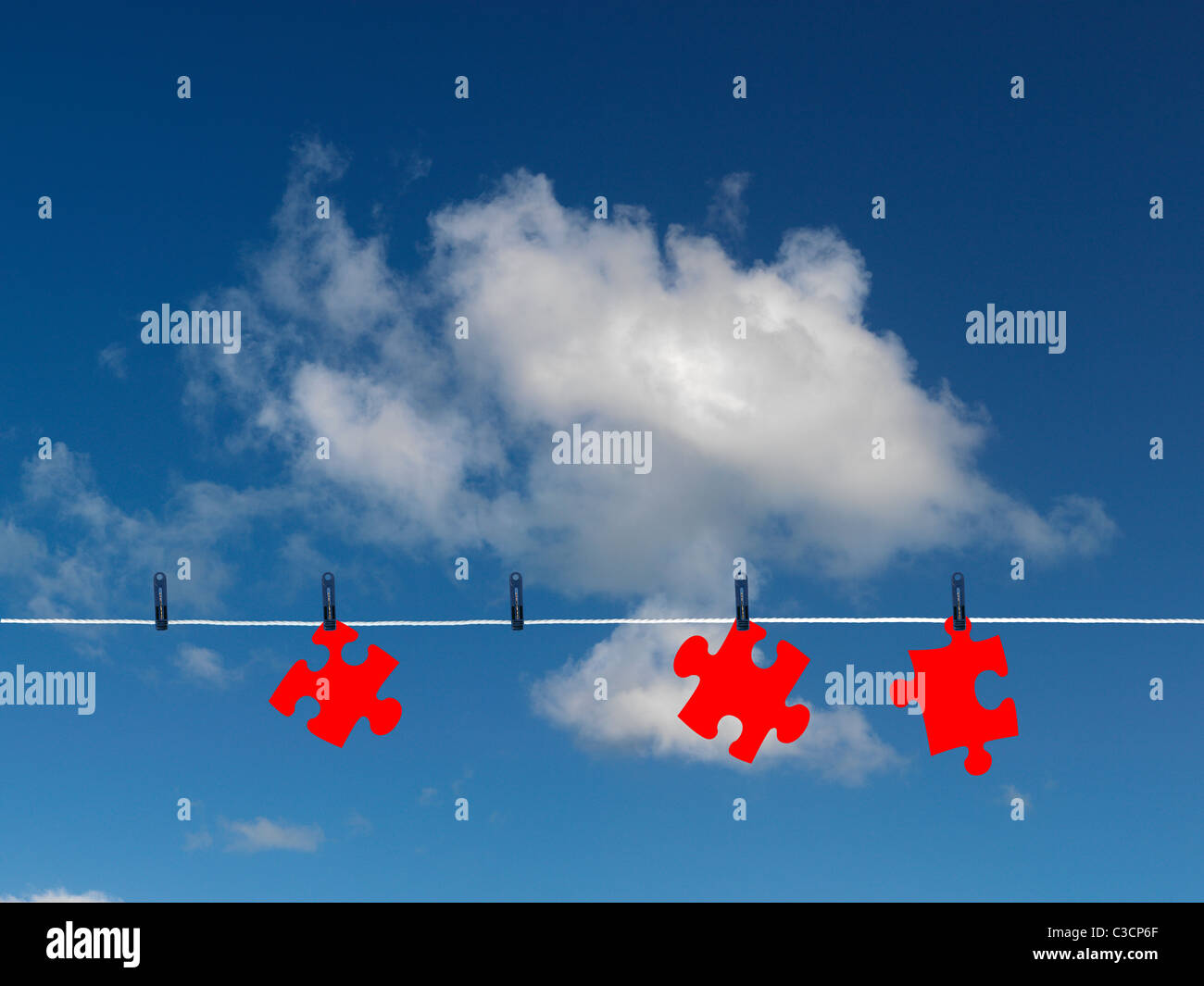 Jigsaw pezzi su una linea di abbigliamento isolata contro un cielo blu Foto Stock