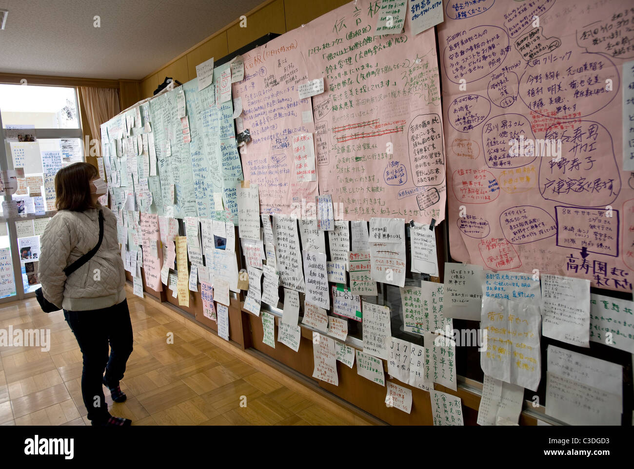 Una donna guarda i messaggi scritti da i superstiti dello tsunami alla ricerca di amici e cari in un rifugio in Rikuzentakata Foto Stock