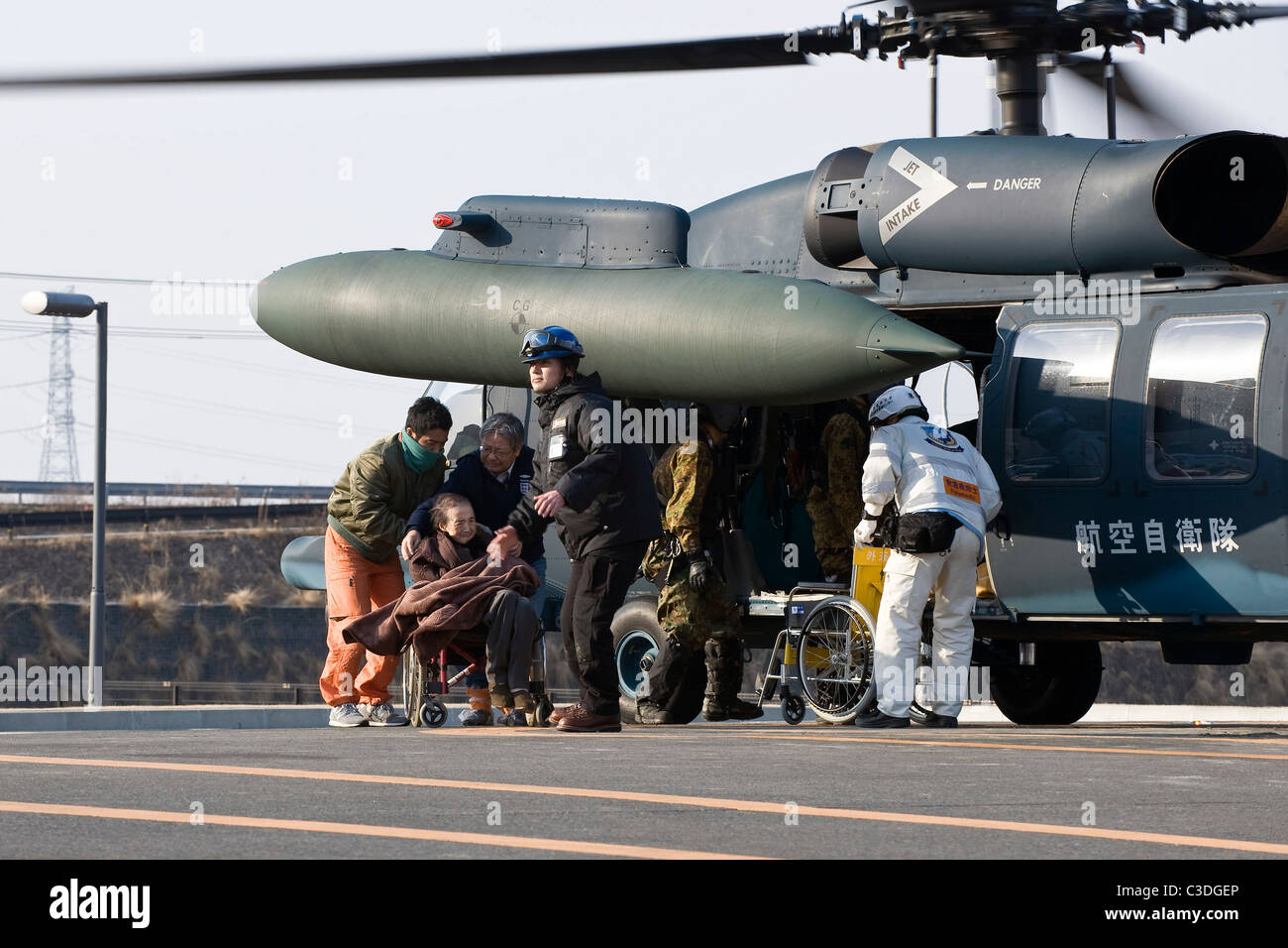 Una donna anziana è aiutato fuori da un elicottero dopo essere evacuato dalla sua casa in un ospedale Ishinomaki, Giappone Foto Stock