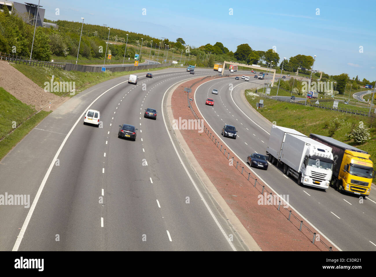 Autostrada M1 in Inghilterra. Girato sulla luminosa giornata soleggiata con cielo blu. Mostra sei corsie della carreggiata. Curva in strada. L'ambiente rurale. Foto Stock