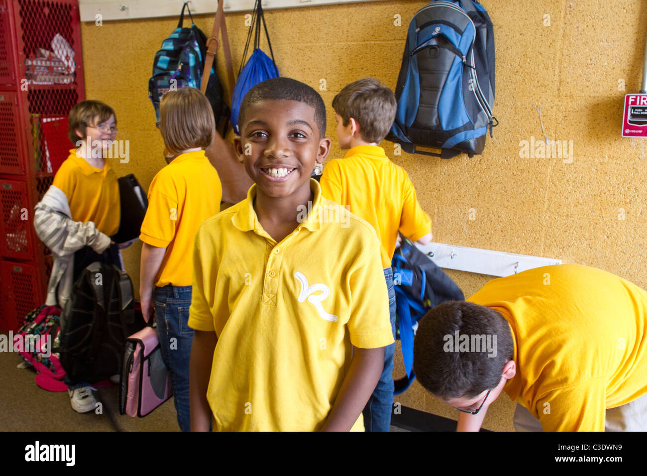 Ragazzo afro-americano indossano uniformi scolastiche shirt sorrisi nel corridoio a Rapoport Academy charter scuola elementare a Waco Texas Foto Stock