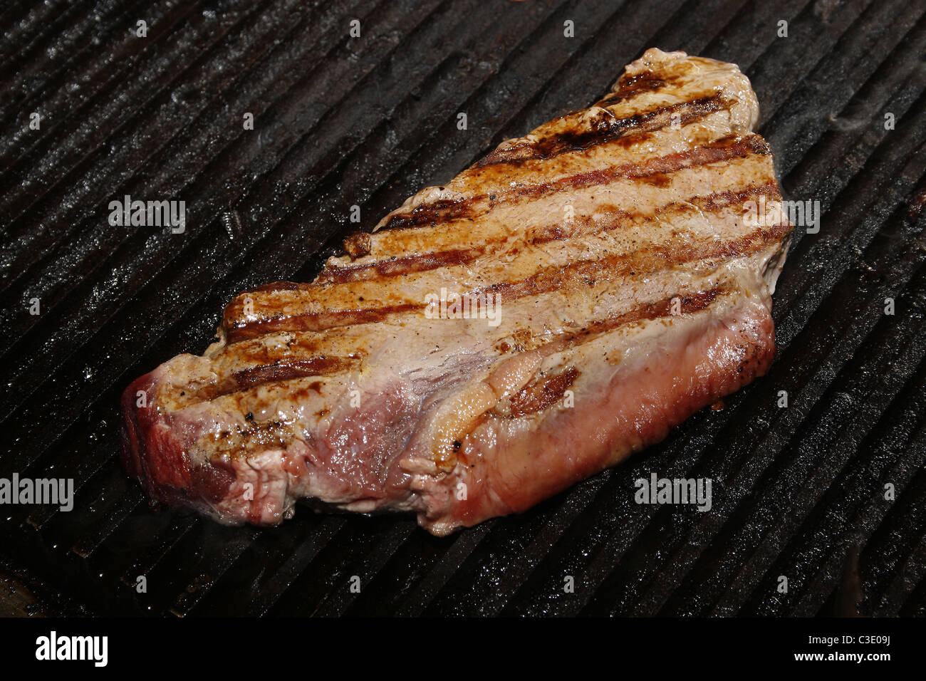 Mezzo raro bistecca di controfiletto la cottura su piastra nera Foto Stock