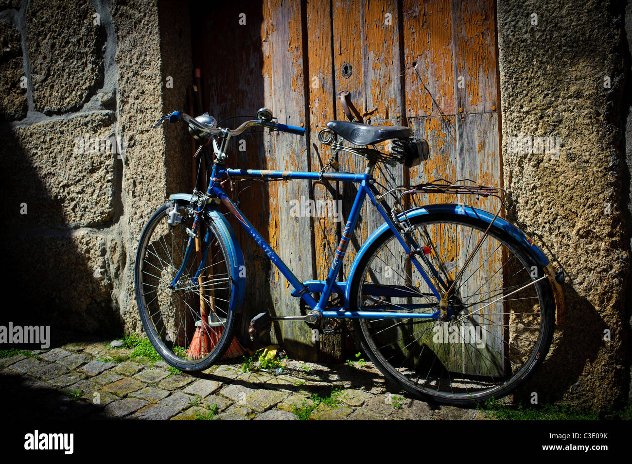 Vecchia bicicletta standard blu appoggiato contro una porta a spiovente in Portogallo centrale Foto Stock