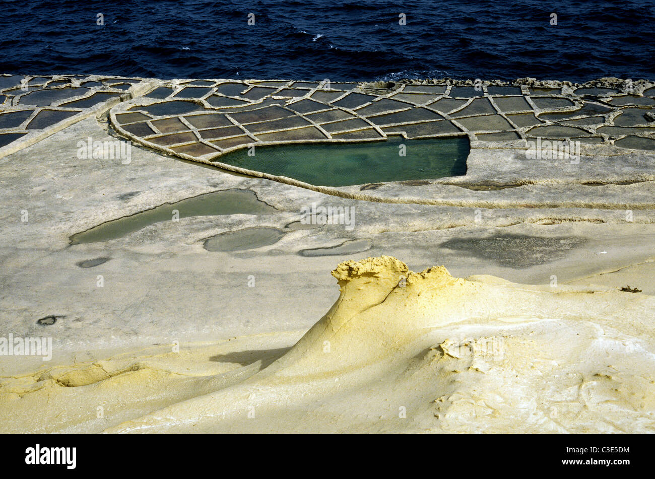 Sale pentole di evaporazione tagliato in arenaria dal Mare Mediterraneo a Xwejni Bay sull'isola Maltese di Gozo. Foto Stock