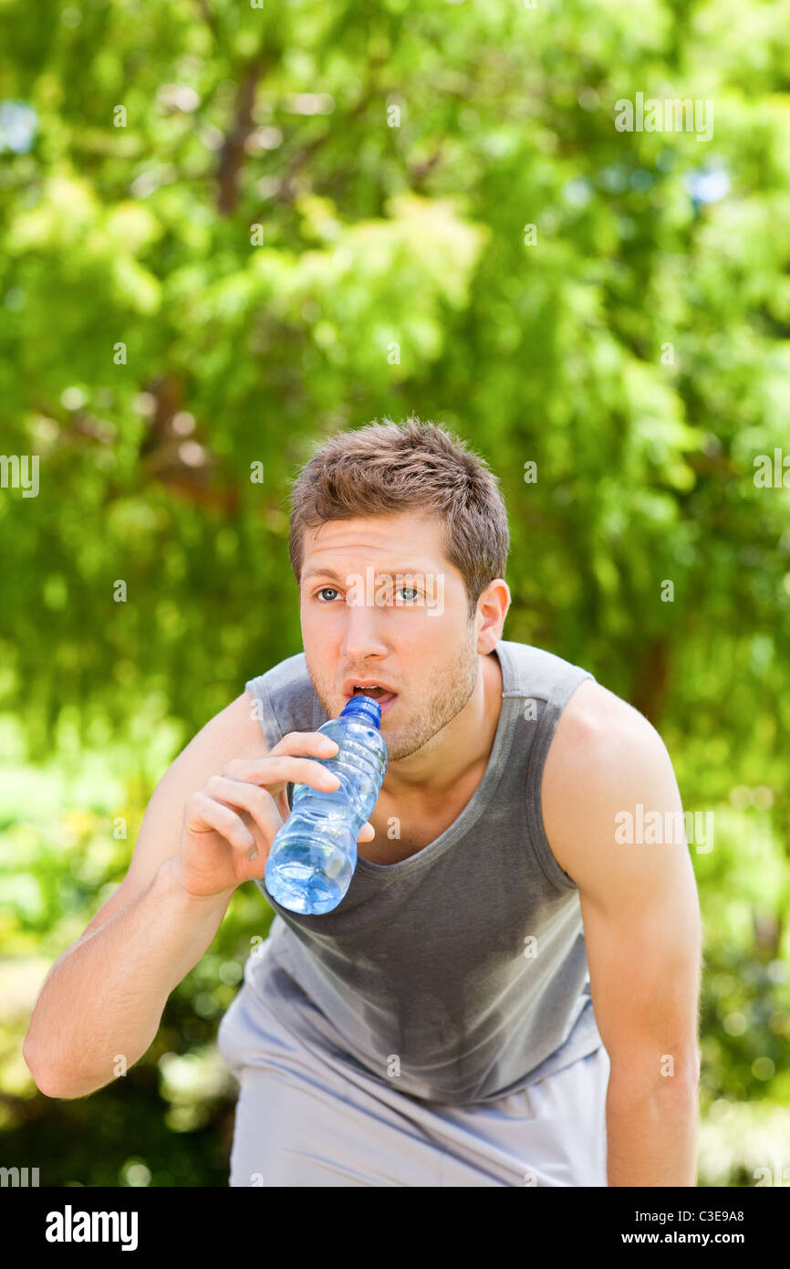 Uomo sportivo acqua potabile nel parco Foto Stock