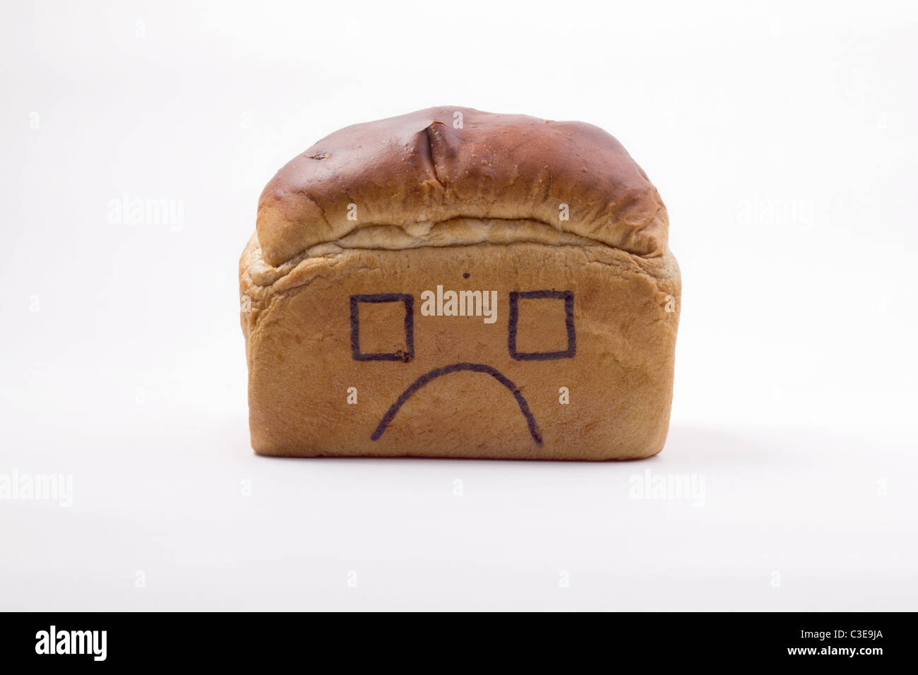 Immagine concettuale di pane tradizionale con un infelice faccia disegnato su. Il nostro pane quotidiano, domestici, home vita, ciò che consumiamo. Foto Stock