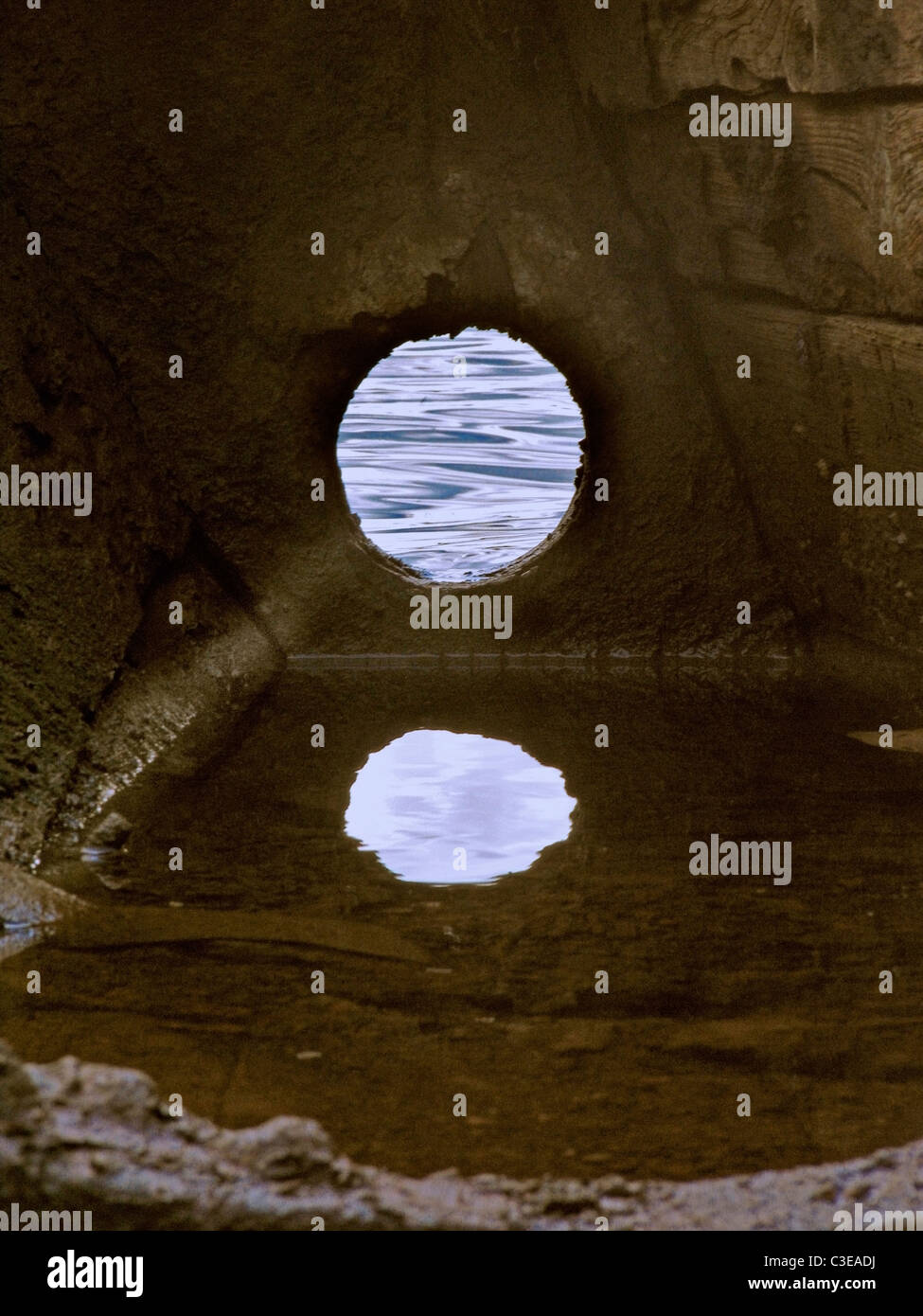 La riflessione del foro in una parte spezzata di barca da pesca in acqua, Ratnagiri, Maharasthra, India Foto Stock